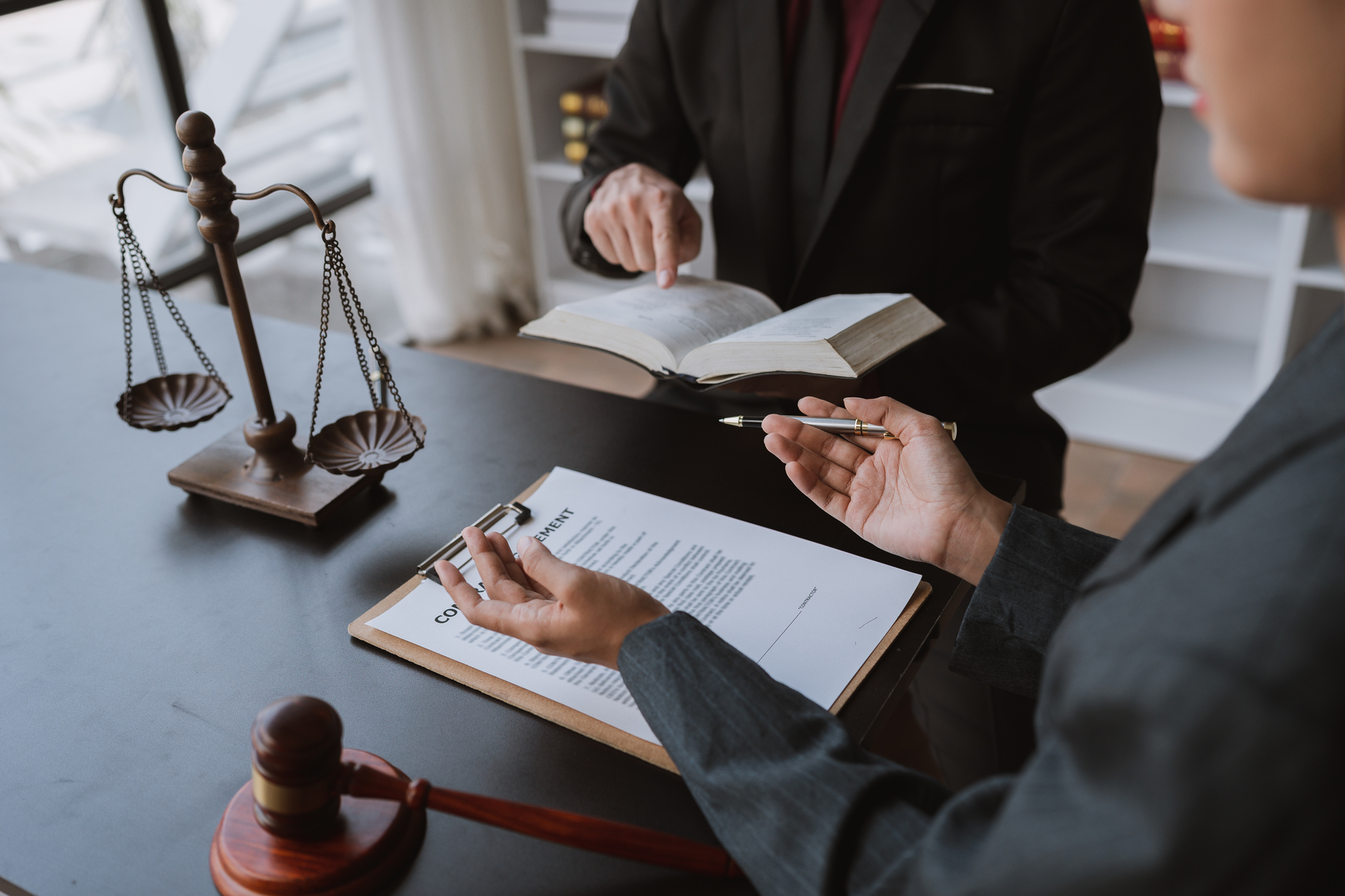 Abogado explicando a un cliente los pasos previos antes de presentar un recurso contencioso administrativo, con documentos oficiales.